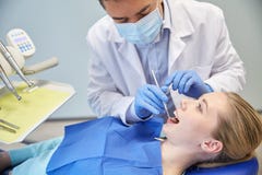 Dentiste masculin dans le masque vérifiant les dents patientes femelles images libres de droits Dentiste masculin dans le masque vérifiant les dents patientes femelles images libres de droits