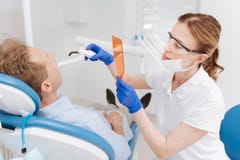 Dentiste scrupuleux important blanchissant des dents de patients image libre de droits Dentiste scrupuleux important blanchissant des dents de patients image libre de droits