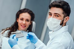 Dentiste vérifiant et choisissant la couleur des dents de la jeune femme regardant la fin de caméra vers le haut de la vue Foyer photographie stock Dentiste vérifiant et choisissant la couleur des dents de la jeune femme regardant la fin de caméra vers le haut de la vue Foyer photographie stock