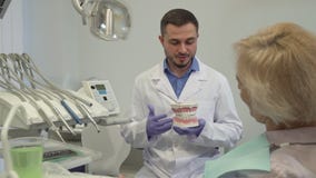 Dentystów explaines coś na układzie zęby jego żeński klient zdjęcie wideo Dentystów explaines coś na układzie zęby jego żeński klient zdjęcie wideo