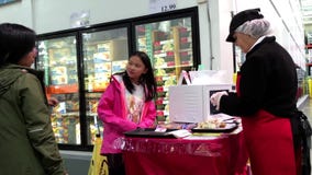 Dependienta que ofrece muestras de alimentos mexicanas de los burritos a los clientes Dependienta que ofrece muestras de alimentos mexicanas de los burritos a los clientes