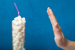 Dependência do açúcar e o trajeto à obesidade e ao diabetes, conceito A mão mostra uma parada, um vidro com uma bebida do açúcar fotos de stock royalty free Dependência do açúcar e o trajeto à obesidade e ao diabetes, conceito A mão mostra uma parada, um vidro com uma bebida do açúcar fotos de stock royalty free