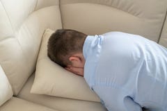 Depressed teenager lying face down on sofa stock photography Depressed teenager lying face down on sofa stock photography