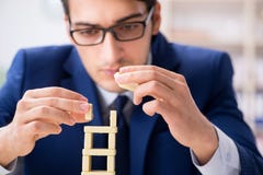 Der junge Geschäftsmanngebäude-Dominoturm im Büro stockfoto Der junge Geschäftsmanngebäude-Dominoturm im Büro stockfoto