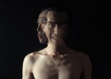 Der merkwürdige Mann stand in der Dunkelheit mit einem schlechten Lächeln auf seinem Gesicht und betrachtete die Kamera lizenzfreies stockbild Der merkwürdige Mann stand in der Dunkelheit mit einem schlechten Lächeln auf seinem Gesicht und betrachtete die Kamera lizenzfreies stockbild