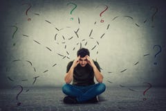 Der verwirrte und m?de junge Mann, der auf dem Boden setzt, h?lt die H?nde zur Stirn, die hinunter durchdachtes umgeben durch ver lizenzfreie stockbilder Der verwirrte und m?de junge Mann, der auf dem Boden setzt, h?lt die H?nde zur Stirn, die hinunter durchdachtes umgeben durch ver lizenzfreie stockbilder