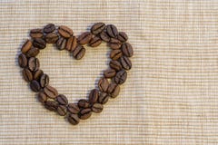 Des grains de café sont présentés sous forme de coeur sur un napk beige images stock Des grains de café sont présentés sous forme de coeur sur un napk beige images stock