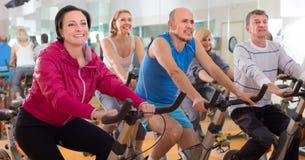 Des personnes plus âgées font des sports sur des vélos d'exercice photo stock Des personnes plus âgées font des sports sur des vélos d'exercice photo stock