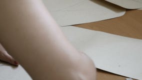 Desenhador de moda fêmea novo que trabalha em sua sala de exposições que faz testes padrões para costurar nos materiais de matéri filme Desenhador de moda fêmea novo que trabalha em sua sala de exposições que faz testes padrões para costurar nos materiais de matéri filme