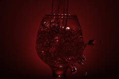 Det enkla stillebenfotoet av whiskyexponeringsglas, vattenstrålen och fördunklar rött l arkivfoton Det enkla stillebenfotoet av whiskyexponeringsglas, vattenstrålen och fördunklar rött l arkivfoton