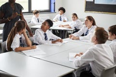 Detail Of Female High School Tutor Helping Students Wearing Uniform Seated Around Tables In Lesson stock images Detail Of Female High School Tutor Helping Students Wearing Uniform Seated Around Tables In Lesson stock images