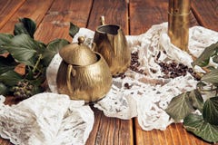 Details captured a brass milk jug and a brass sugar bowl, ivy on an old, wooden table top with coffee beans stock photos Details captured a brass milk jug and a brass sugar bowl, ivy on an old, wooden table top with coffee beans stock photos