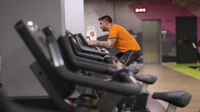 Fit man working out on exercise bike at the gym with bokeh