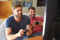Deux amis masculins dans des pyjamas jouant le jeu vidéo ensemble image stock Deux amis masculins dans des pyjamas jouant le jeu vidéo ensemble image stock