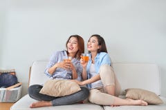 Deux amis parlant et appréciant un jus d'orange se reposant sur un divan dans le salon à la maison image libre de droits Deux amis parlant et appréciant un jus d'orange se reposant sur un divan dans le salon à la maison image libre de droits