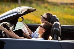 Deux belles jeunes femmes dans des lunettes de soleil s'asseyent dans un cabriolet noir et sourient un jour ensoleillé L'un d'ent photo libre de droits Deux belles jeunes femmes dans des lunettes de soleil s'asseyent dans un cabriolet noir et sourient un jour ensoleillé L'un d'ent photo libre de droits