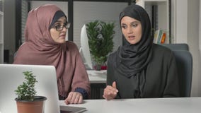 Deux belles jeunes filles dans les hijabs s'asseyent dans le bureau et discutent des programmes, affaires, dialogue, conversation banque de vidéos Deux belles jeunes filles dans les hijabs s'asseyent dans le bureau et discutent des programmes, affaires, dialogue, conversation banque de vidéos