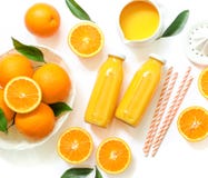 Deux bouteilles en verre de jus, de pailles et d'oranges d'orange fraîches d'isolement sur la vue supérieure de fond blanc Image stock Deux bouteilles en verre de jus, de pailles et d'oranges d'orange fraîches d'isolement sur la vue supérieure de fond blanc Image stock