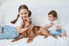 Deux bébés, soeurs jouent sur le sofa blanc avec le chien rouge image libre de droits Deux bébés, soeurs jouent sur le sofa blanc avec le chien rouge image libre de droits