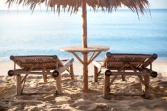 Deux canapés et tables en bambou vides sous le parapluie de paille sur la plage isolée de sable blanc, fond bleu de mer photographie stock libre de droits Deux canapés et tables en bambou vides sous le parapluie de paille sur la plage isolée de sable blanc, fond bleu de mer photographie stock libre de droits
