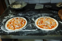 Deux cercles de pâte sur un conseil noir dans un restaurant Cuisson de la pizza photos libres de droits Deux cercles de pâte sur un conseil noir dans un restaurant Cuisson de la pizza photos libres de droits