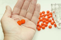 Deux comprimés dans un mensonge orange de coquille sur la paume de votre main images stock Deux comprimés dans un mensonge orange de coquille sur la paume de votre main images stock