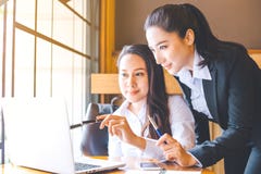 Deux femmes d'affaires travaillent sur un ordinateur portable, tenant a image stock Deux femmes d'affaires travaillent sur un ordinateur portable, tenant a image stock