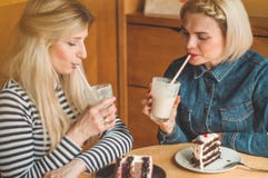 Deux femmes heureuses s'asseyant dans un caf? et prenant des selfies au t?l?phone, boivent un cocktail photo stock Deux femmes heureuses s'asseyant dans un caf? et prenant des selfies au t?l?phone, boivent un cocktail photo stock