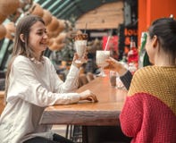 Deux femmes heureuses s'asseyent dans un café, buvant des milkshakes photo libre de droits Deux femmes heureuses s'asseyent dans un café, buvant des milkshakes photo libre de droits