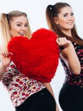 Deux femmes heureuses tenant l'oreiller en forme de coeur photo libre de droits Deux femmes heureuses tenant l'oreiller en forme de coeur photo libre de droits