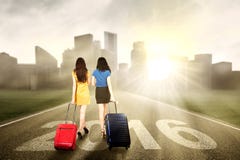 Deux femmes portant la valise et la promenade sur la route photo stock Deux femmes portant la valise et la promenade sur la route photo stock