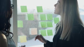 Deux femmes se tenant devant le bureau dans le bureau discutent la stratégie clips vidéos Deux femmes se tenant devant le bureau dans le bureau discutent la stratégie clips vidéos
