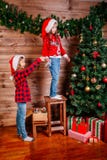 Deux filles mignonnes de petit enfant décore l'arbre de Noël à l'intérieur images libres de droits Deux filles mignonnes de petit enfant décore l'arbre de Noël à l'intérieur images libres de droits