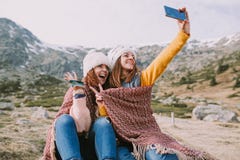 Deux filles s'asseyent dans le pré et prennent une photo avec leur mobile photos stock Deux filles s'asseyent dans le pré et prennent une photo avec leur mobile photos stock