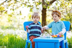 Deux garçons mignons de petit enfant portant des oreilles de lapin de Pâques, des oeufs colorés de peinture et ayant l'amusement images stock Deux garçons mignons de petit enfant portant des oreilles de lapin de Pâques, des oeufs colorés de peinture et ayant l'amusement images stock