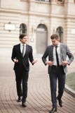 Deux hommes d'affaires élégants parlant et souriant dehors Photo stock Deux hommes d'affaires élégants parlant et souriant dehors Photo stock