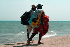 Deux hommes à la peau foncée, les négociants de plage marchant le long des rivages images stock Deux hommes à la peau foncée, les négociants de plage marchant le long des rivages images stock