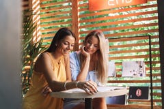 Deux jeunes amies gaies s'asseyant au caf? ? l'int?rieur photo libre de droits Deux jeunes amies gaies s'asseyant au caf? ? l'int?rieur photo libre de droits