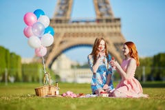 Deux jeunes femmes ayant le pique-nique près de Tour Eiffel à Paris, France photo stock Deux jeunes femmes ayant le pique-nique près de Tour Eiffel à Paris, France photo stock