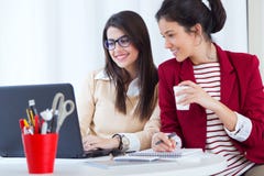 Deux jeunes femmes d'affaires travaillant avec l'ordinateur portable dans son bureau image libre de droits Deux jeunes femmes d'affaires travaillant avec l'ordinateur portable dans son bureau image libre de droits