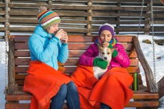 Deux jeunes femmes sirotant le café chaud dans une chaise de basculage en bois dessus Images stock Deux jeunes femmes sirotant le café chaud dans une chaise de basculage en bois dessus Images stock
