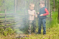Deux jeunes garçons jouent à côté d'un feu de tabagisme image stock Deux jeunes garçons jouent à côté d'un feu de tabagisme image stock