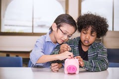 Deux petits garçons mettant l'argent dans la tirelire pour la future épargne photo stock Deux petits garçons mettant l'argent dans la tirelire pour la future épargne photo stock