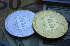 Deux pièces de Bitcoin se trouvent sur le fond des billets de devise photos stock Deux pièces de Bitcoin se trouvent sur le fond des billets de devise photos stock