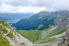 Deux randonneurs descendant dans une vallée dans les moutains d'Allgaeu un jour nuageux, Autriche Photo stock Deux randonneurs descendant dans une vallée dans les moutains d'Allgaeu un jour nuageux, Autriche Photo stock