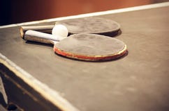 Deux raquettes et un mensonge blanc de boule sur une vieille table de ping-pong image stock Deux raquettes et un mensonge blanc de boule sur une vieille table de ping-pong image stock
