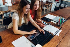 Deux étudiantes de sourire faisant le travail ensemble utilisant l'ordinateur portable se reposant à la pièce d'étude images libres de droits Deux étudiantes de sourire faisant le travail ensemble utilisant l'ordinateur portable se reposant à la pièce d'étude images libres de droits