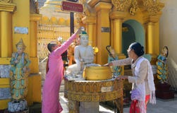 Devotos budistas que bañan las estatuas de Buda en la pagoda de Shwedagon Foto de archivo libre de regalías Devotos budistas que bañan las estatuas de Buda en la pagoda de Shwedagon Foto de archivo libre de regalías