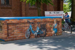Deze muurschildering die een vrij jong meisje afschilderen die en in een blauwe elektrische fiets glimlachen stoppen werd gezien royalty-vrije stock fotografie Deze muurschildering die een vrij jong meisje afschilderen die en in een blauwe elektrische fiets glimlachen stoppen werd gezien royalty-vrije stock fotografie