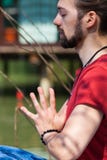 Dia de verão da ioga da prática do homem novo pelas mãos do lago na posição de cumprimento do namaste sobre o chakra do coração fotografia de stock Dia de verão da ioga da prática do homem novo pelas mãos do lago na posição de cumprimento do namaste sobre o chakra do coração fotografia de stock